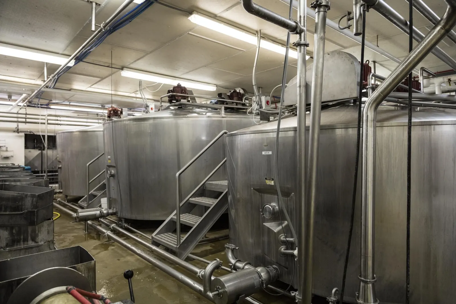 Sala de producción de una industria alimentaria con cubas de acero inoxidable y tuberías