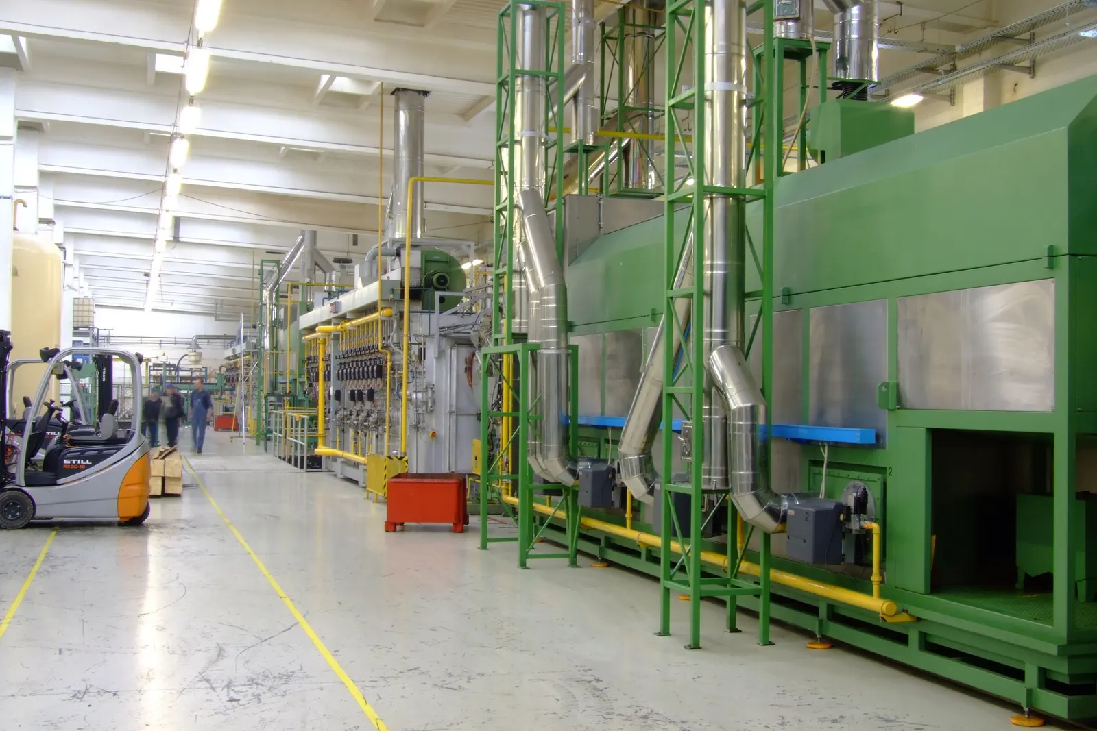 Nave industrial con una línea de producción, pasillo señalizado y una carretilla elevadora