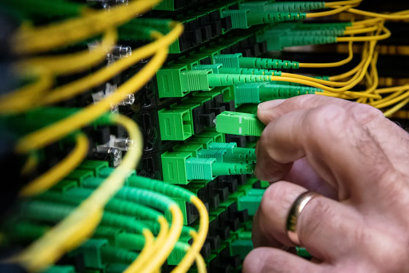 Manos de un técnico conectando cables en un panel de comunicaciones